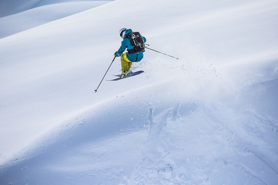 Young male skier jumping in the deep powder snow, Andermatt, Uri, Switzerland