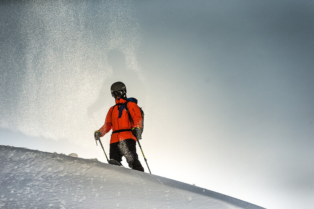 Young male skier standing in the deep powder snow apart the slopes in the mountains, Andermatt, Uri, Switzerland