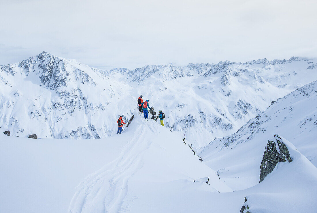 Vier junge Skifahrer stehen am Gipfel eines Berges, Andermatt, Uri, Schweiz