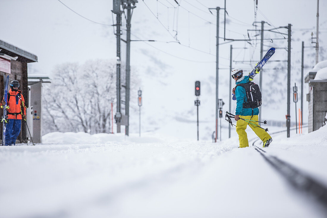 Two young male skiers at a snow-covered litte rail station, Andermatt, Uri, Switzerland