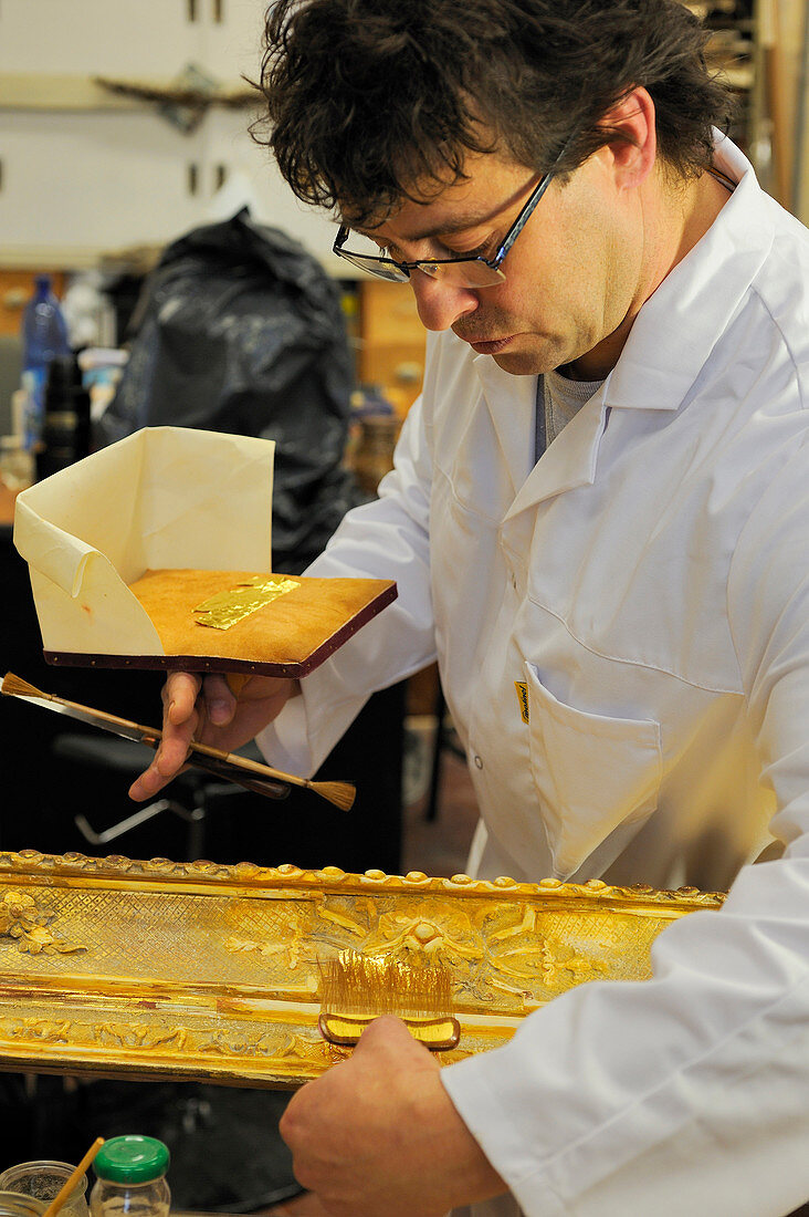 France, Yvelines, Chateau de Versailles, the castle restoration workshop, gilt workshop, Laurent Hissier working on a frame