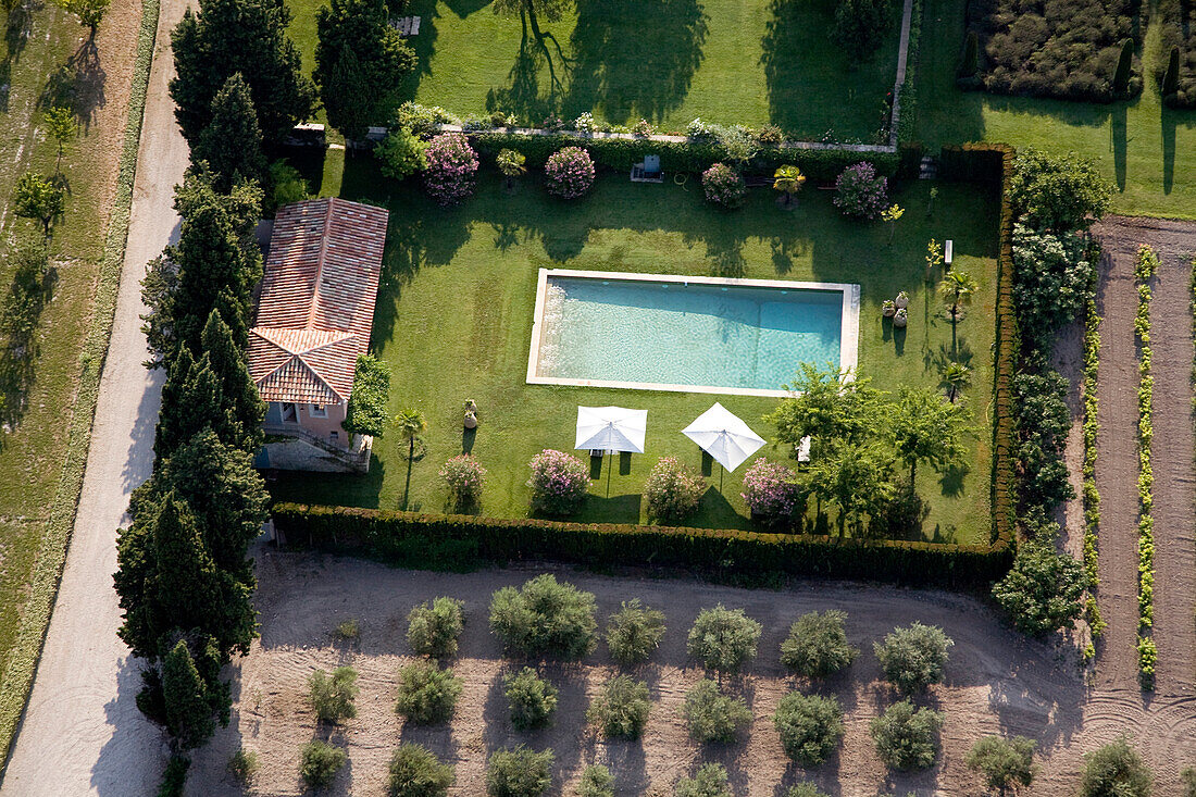 France, Bouches du Rhone, Massif des Alpilles, Parc Naturel Regional des Alpilles, near Mouries, maison or farmhouse locally known as mas in the olive tree fields with swimmming pool and tennis court (aerial view)
