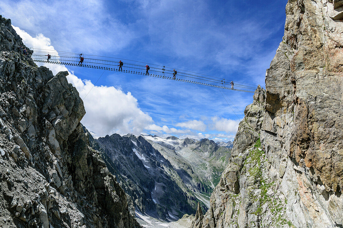 Several persons climbing on fixed-rope Sentiero dei Fiori over big .. Bridge, Sentiero dei Fiori, Adamello-Presanella Group, Trentino, Italy