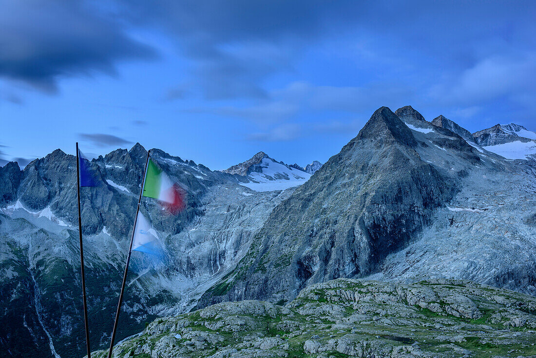 Flags blowing in the wind in front of mountain panorama with Crozzon di Lares and Lobbia Alta, hut rifugio Madron, Adamello-Presanella Group, Trentino, Italy