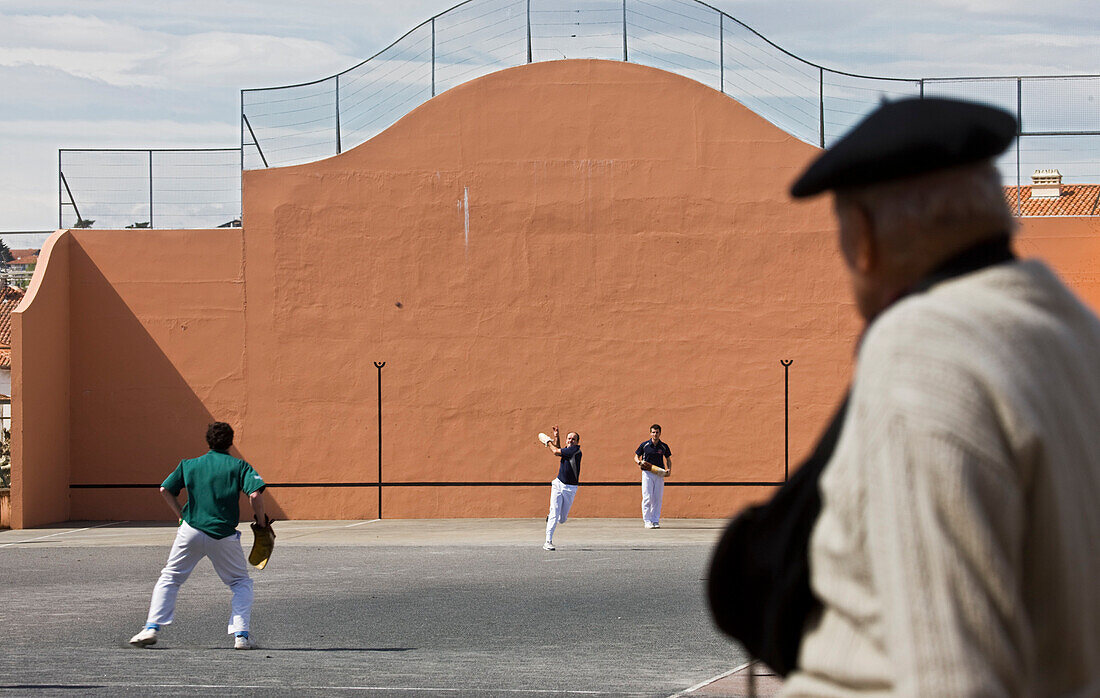 France, Pyrenees Atlantiques, Saint Jean de Luz, man watching a Basque pelota match played in a wall called fronton