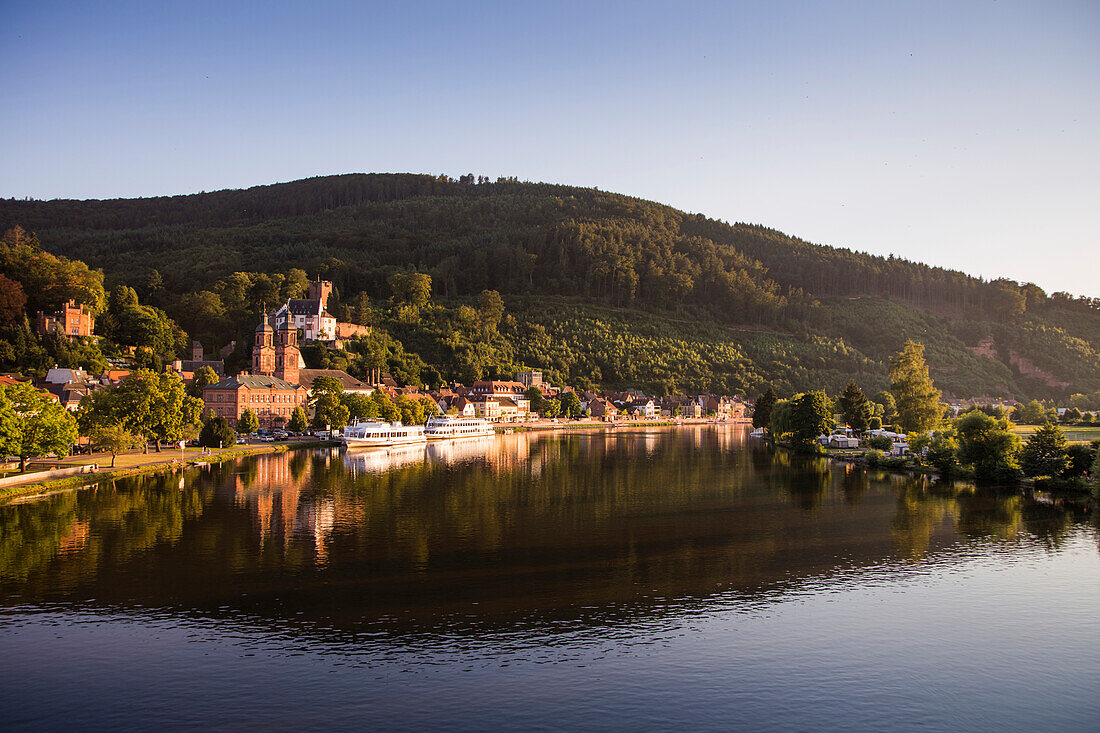 View from Mainbruecke bridge to city and excursion boats on Main river with reflection, Miltenberg, Spessart-Mainland, Bavaria, Germany