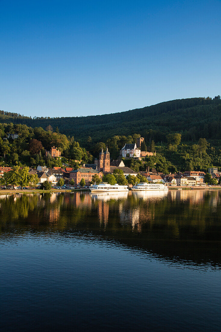 View from Mainbruecke bridge to city and excursion boats on Main river with reflection, Miltenberg, Spessart-Mainland, Bavaria, Germany