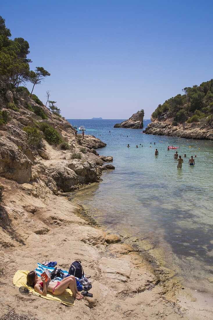Menschen relaxen auf Felsen an der Bucht Cala Portals Vells, Portals Vells, Mallorca, Balearen, Spanien