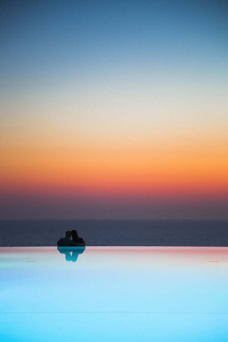 Paar am Rand von Infinity Pool Schwimmbad am Jumeirah Port Soller Hotel & Spa bei Sonnenuntergang, Port Soller, Mallorca, Balearen, Spanien