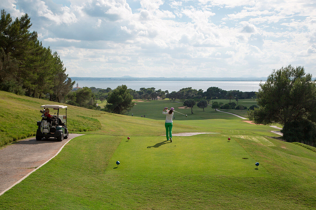 Golfer takes a swing at Club de Golf Alcanada, near Port d'Alcudia, Mallorca, Balearic Islands, Spain