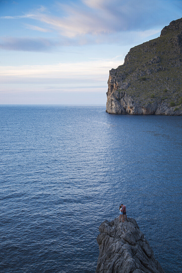 Couple sit on rocks at Cala de Sa Calobra bay and look to the sea, Sa Calobra, Mallorca, Balearic Islands, Spain