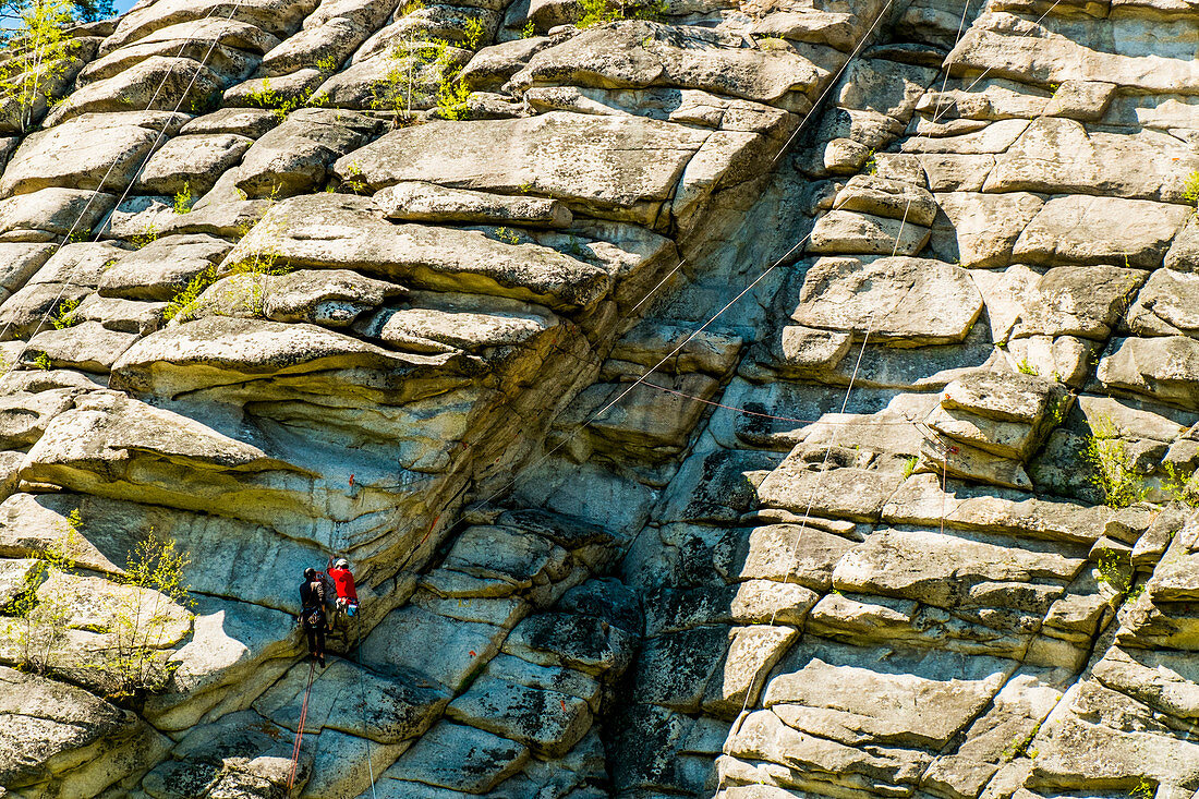 Caucasian friends climbing mountain with rope