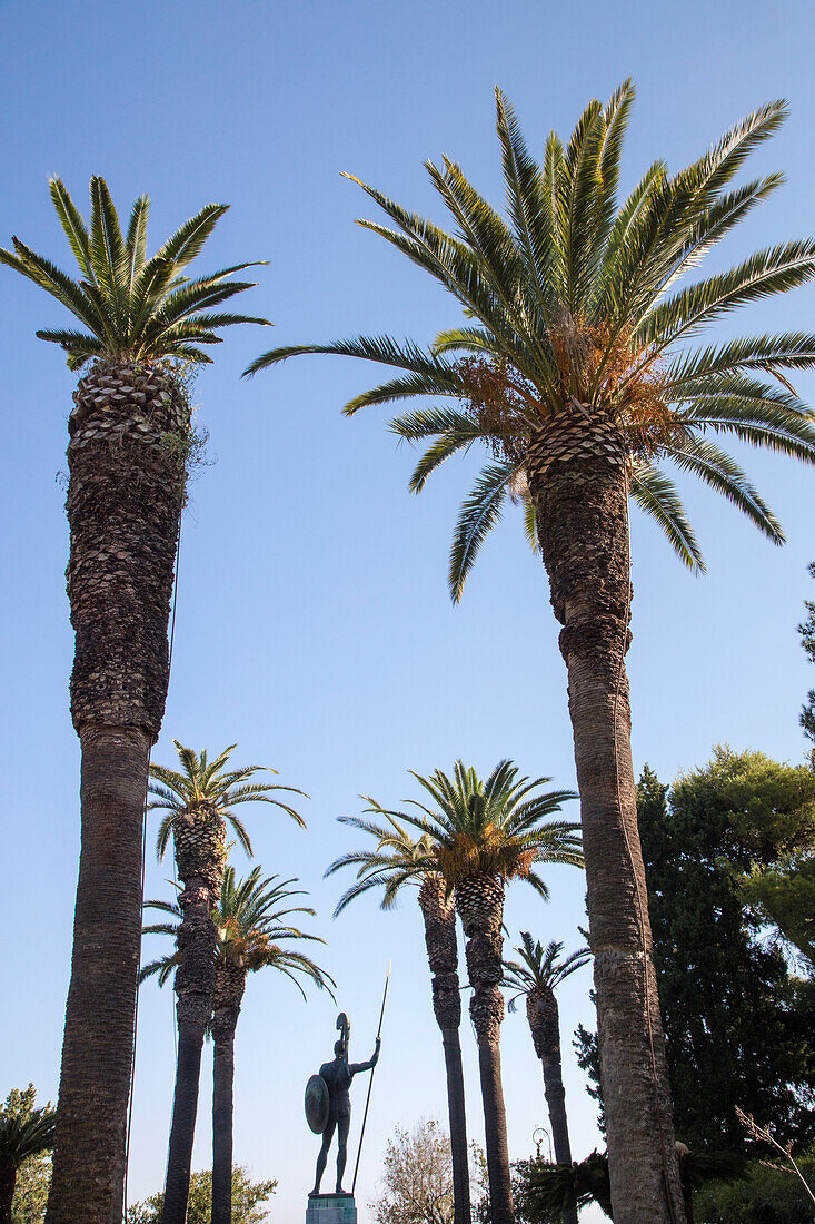 Palmen und Statue in den Gärten von Das Achilleion (der 1891 von Kaiserin Sissi von Österreich erbaute Palast), Gastouri, nahe Kerkyra (Korfu-Stadt), Korfu, Ionische Inseln, Griechenland