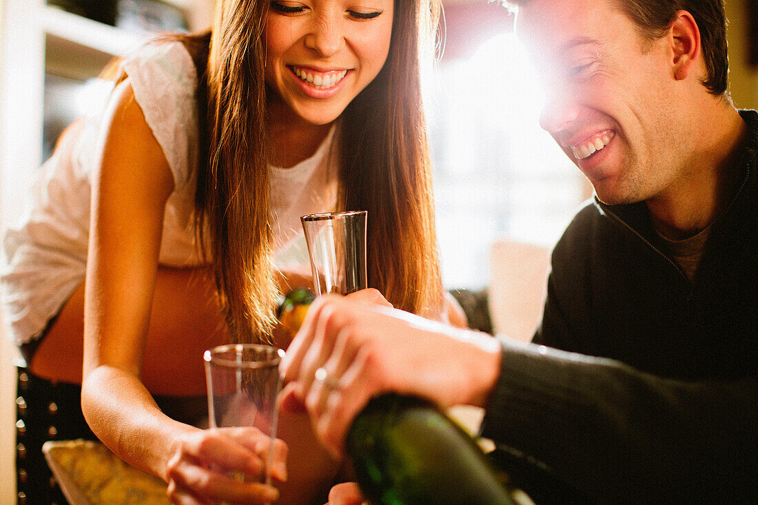 Man pours champagne on his girlfriend's glass during her anniversary.