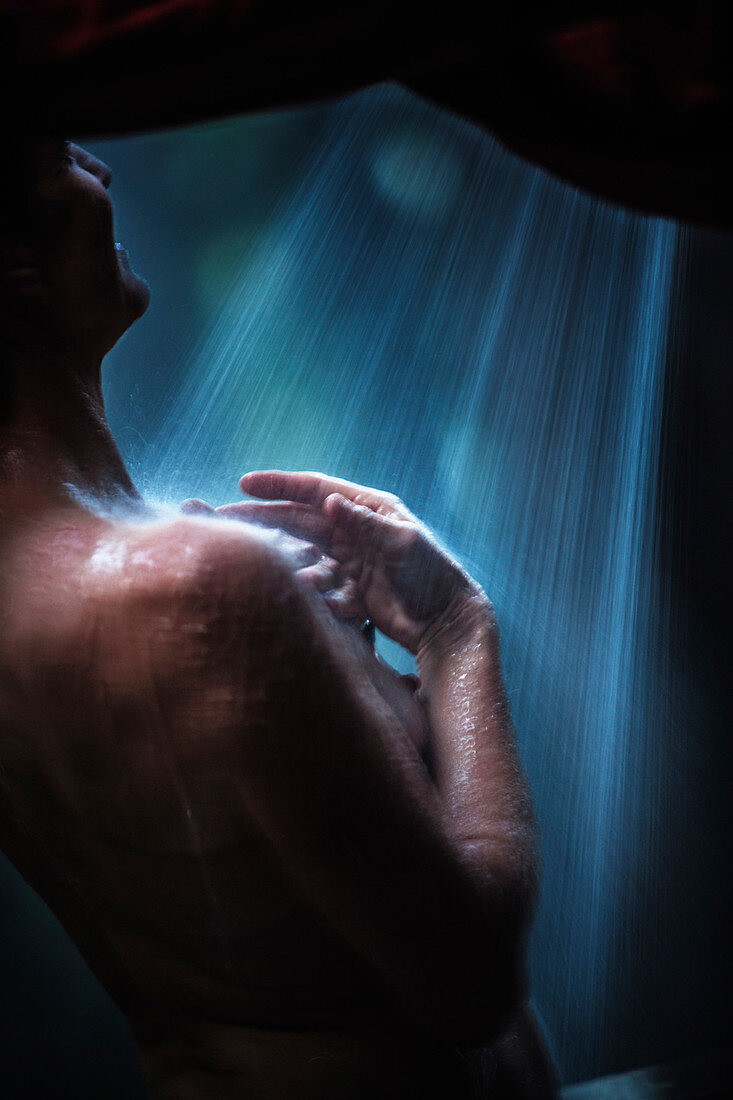 Side view of a woman taking a shower outdoors. Sonoma County, California.