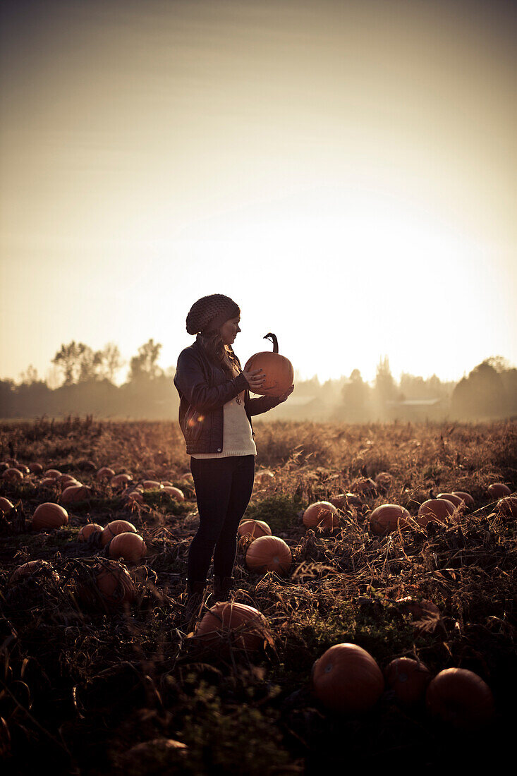 Young woman holding a pumpkin.