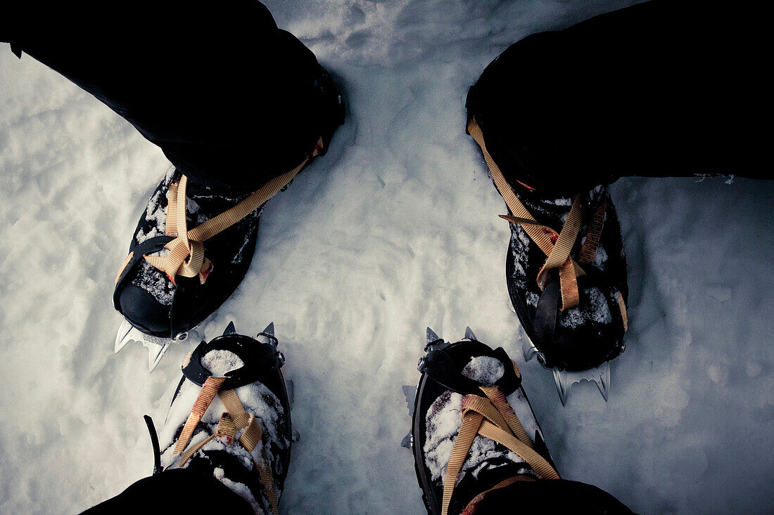Two climber's boots with crampons strapped on.