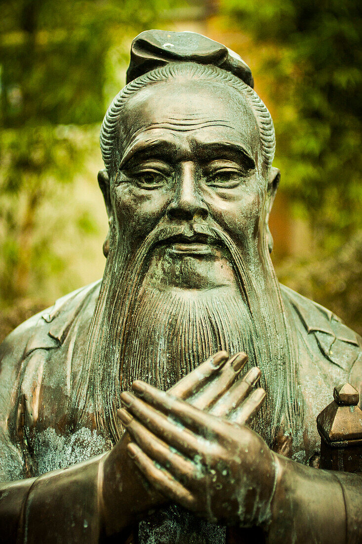 Statue of Confucius against a green background.
