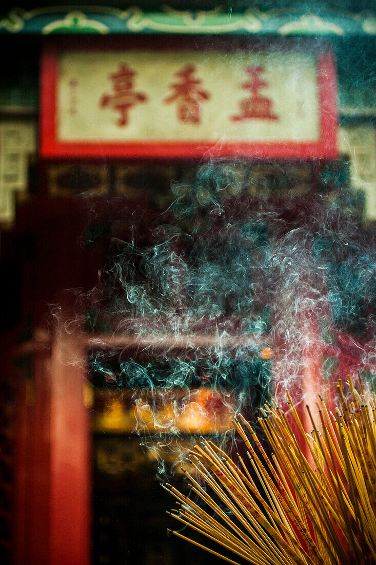 Smoke rising from a large bundle of burning incense sticks at a temple.