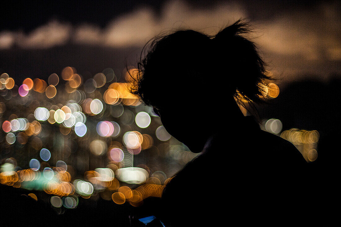 Silhouette of a young woman in a crowded city at night