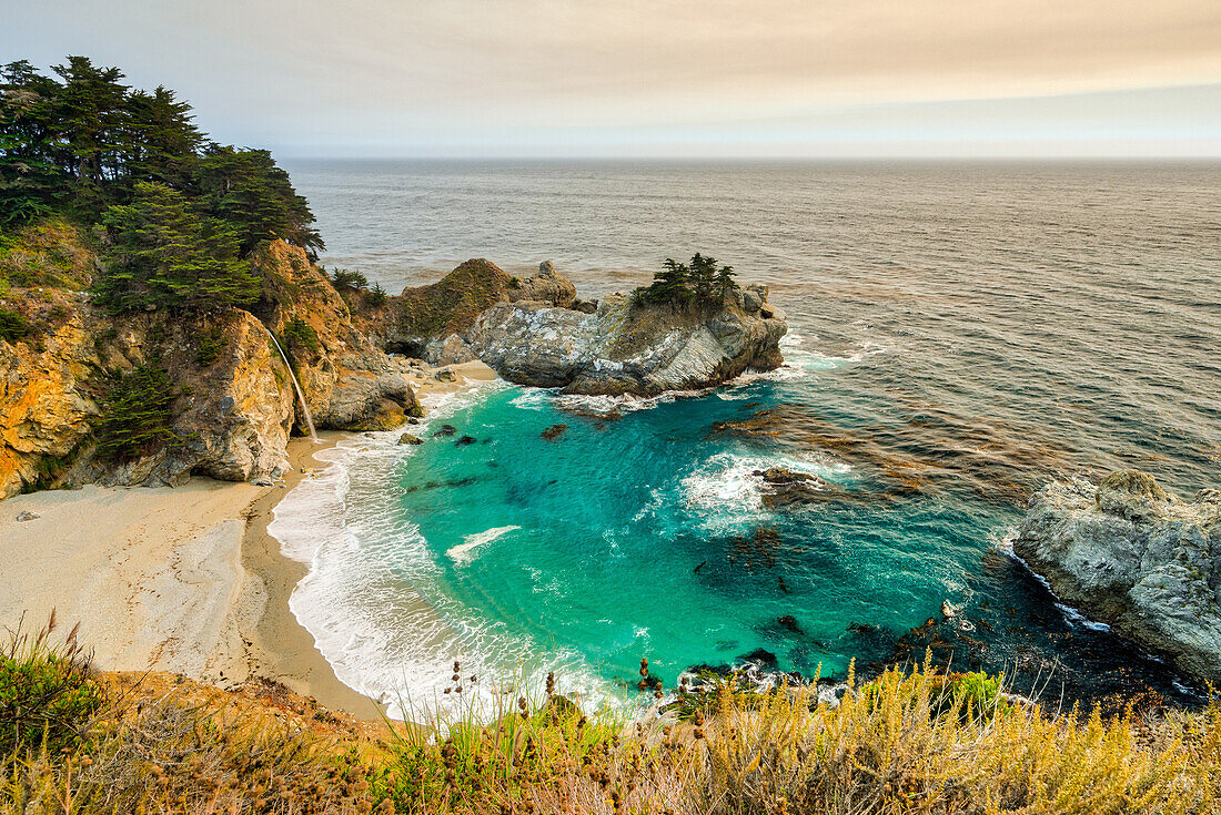 Smoky skies from a nearby wildfire turn the land orange at McWay Falls, California, United States of America, North America