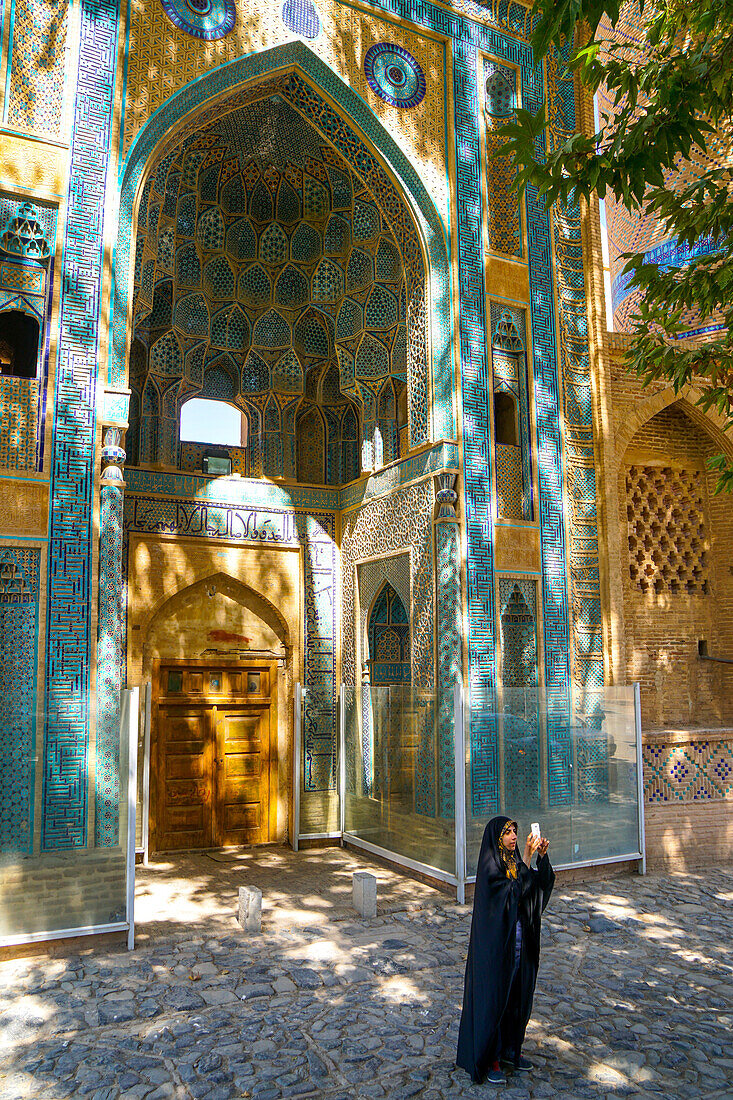 Young Iranian girl in chador taking picture in front of Jameh Mosque, Natanz, Iran, Middle East