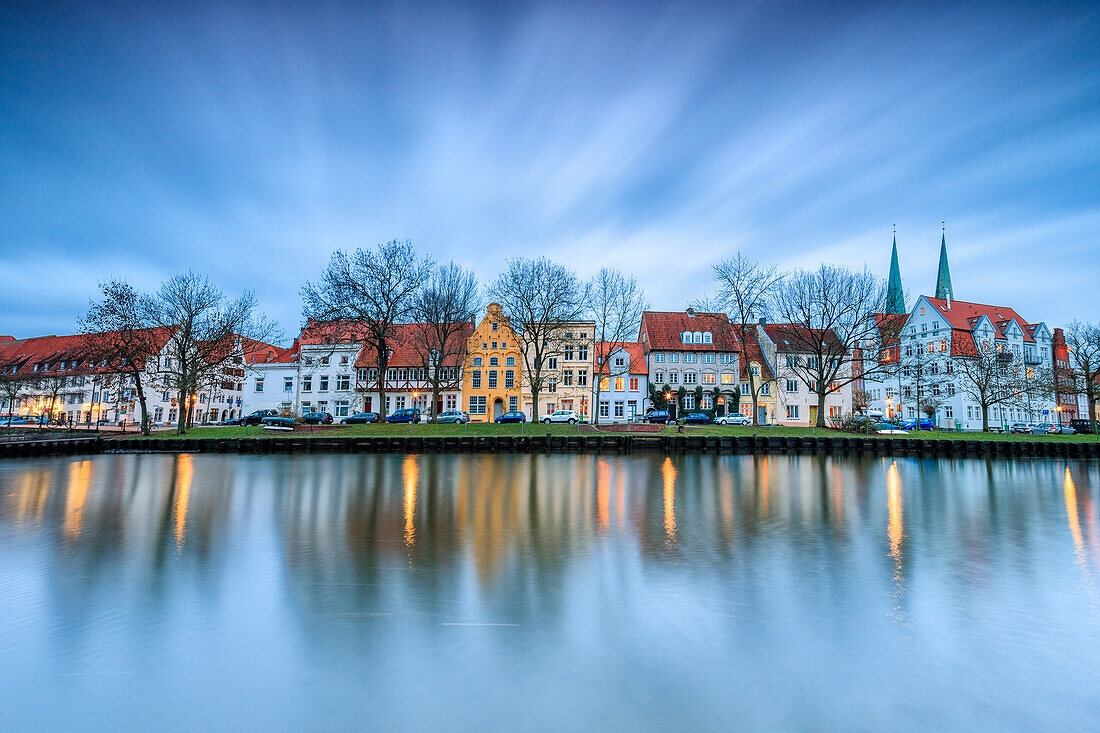 Clouds on the typical houses and towers of cathedral reflected in River Trave at dusk, Lubeck, Schleswig Holstein, Germany, Europe