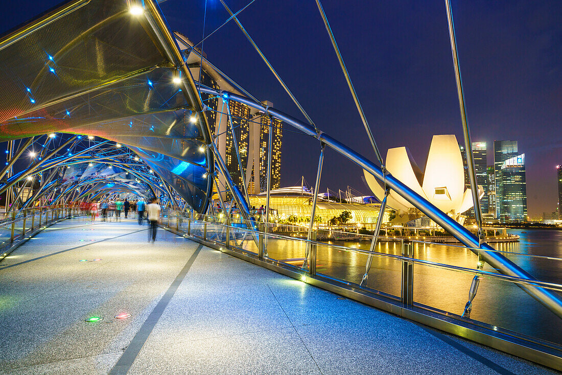 People strolling on the Helix Bridge towards the Marina Bay Sands and ArtScience Museum at night, Marina Bay, Singapore, Southeast Asia, Asia