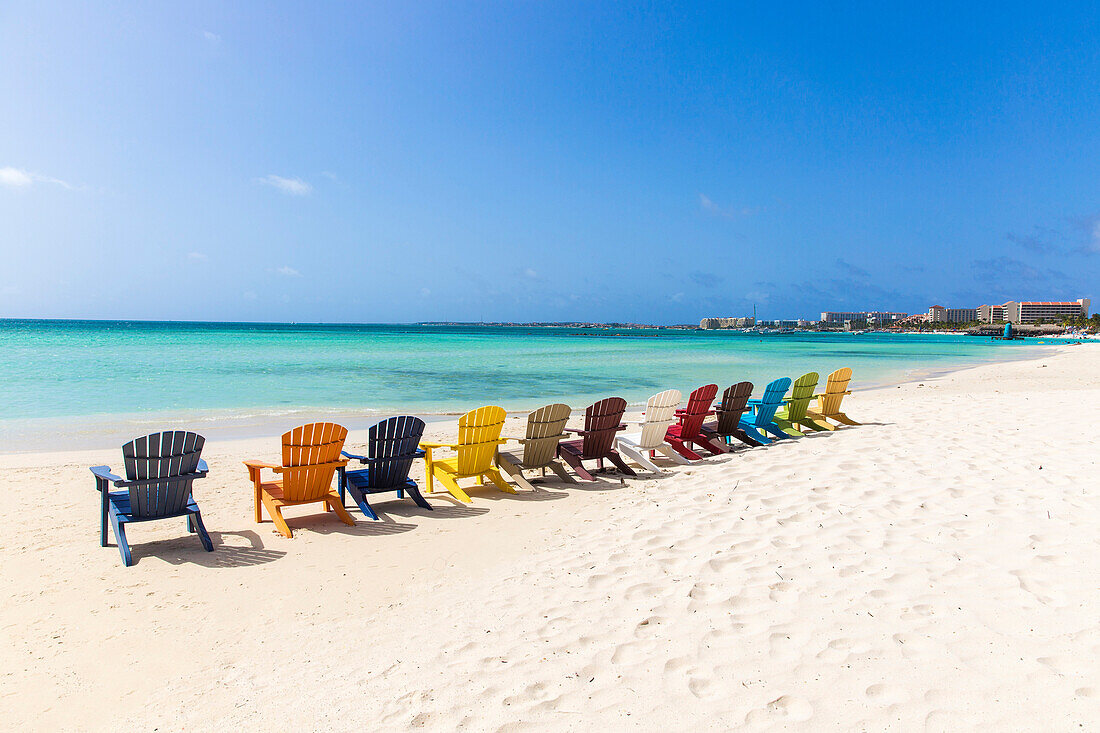 A row of colourful wooden deckchairs on Palm Beach, Aruba, Netherlands Antilles, Caribbean, Central America