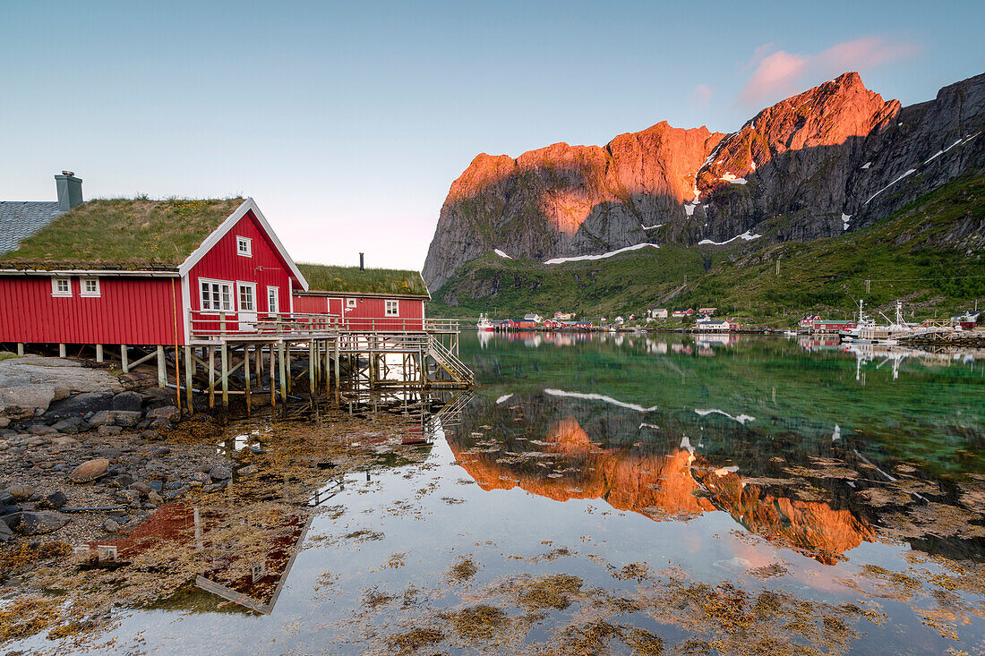 Fishing village and peaks reflected in water under midnight sun, Reine, Nordland county, Lofoten Islands, Arctic, Northern Norway, Scandinavia, Europe