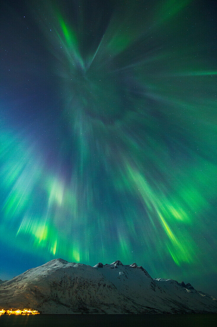 A coronal burst of aurora borealis (Northern Lights) during a solar storm in Northern Norway above a snowy mountain, Norway, Scandinavia, Europe