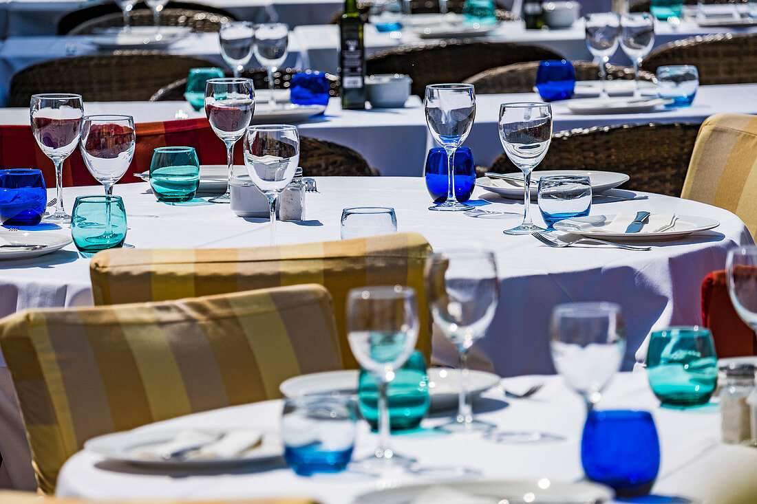 Restaurant tables set with glasses and plates in the harbour of Port d'Andratx, Mallorca, Balearic Islands, Spain