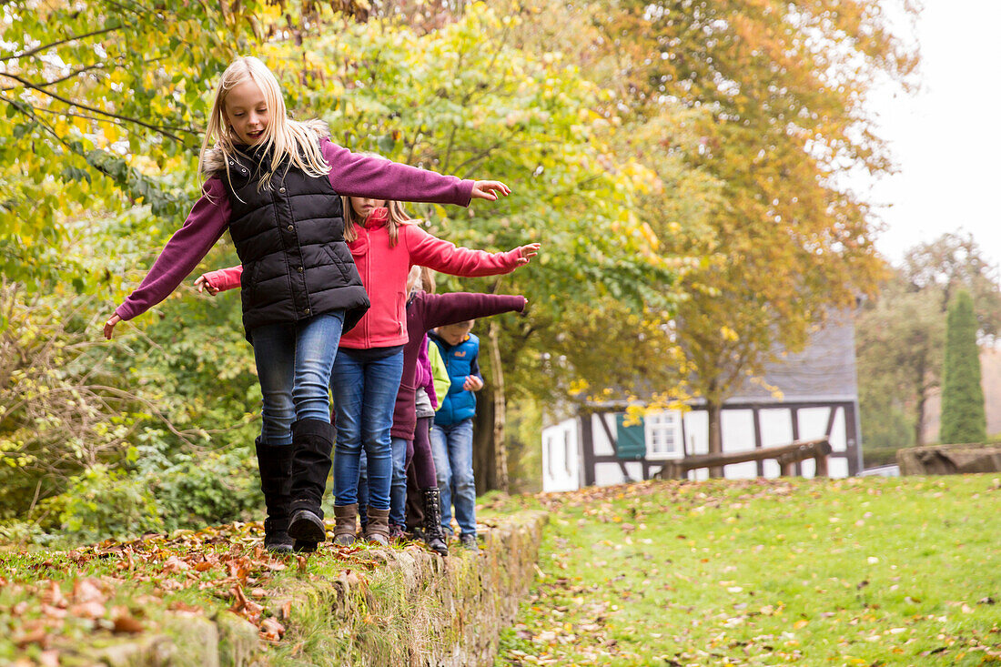 Children play on the Christenberg hill with the old half-timbered house of the verger behind Münchhausen, Burgwald-Ederbergland, Hesse, Germany, Europe