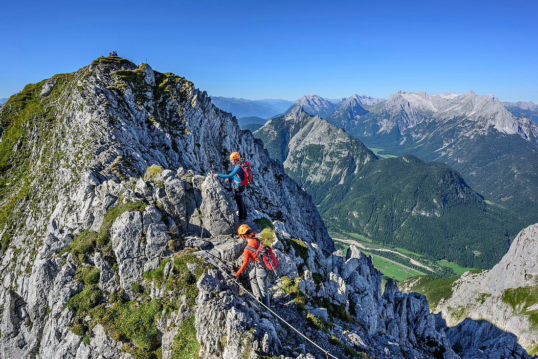 Two women climbing on fixed-rope route Mittenwalder Hoehenweg, Wetterstein range in background, fixed-rope route Mittenwalder Hoehenweg, Karwendel range, Upper Bavaria, Bavaria, Germany