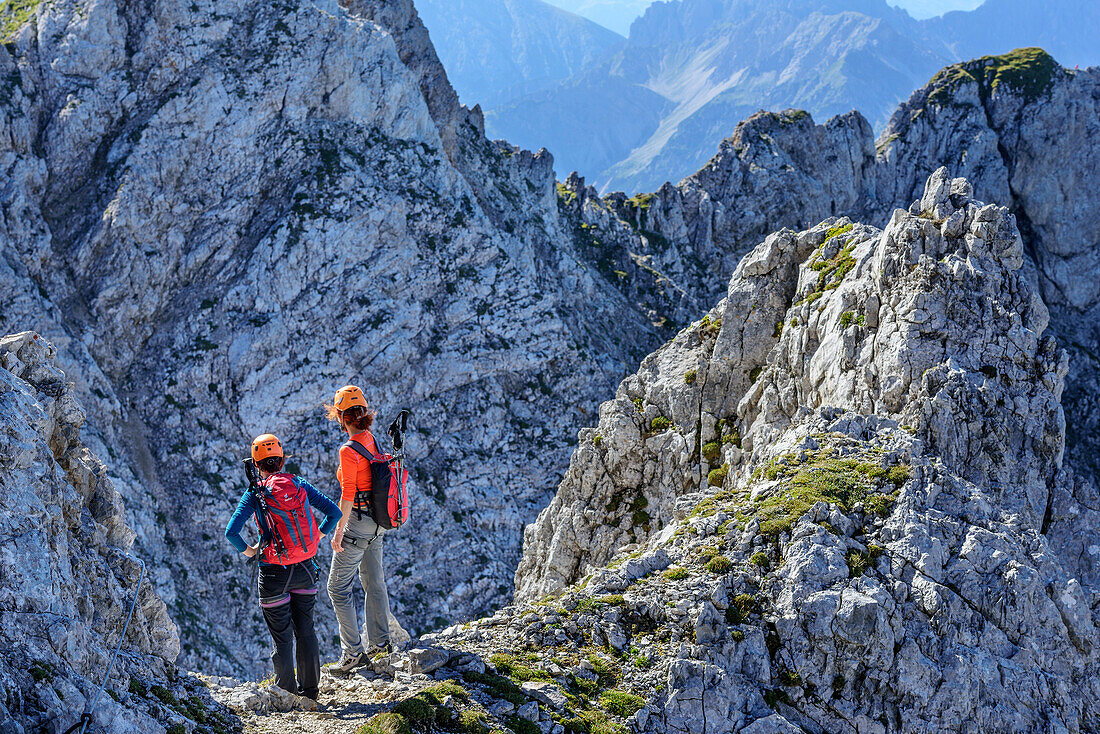 Two women standing in notch, fixed-rope route Mittenwalder Hoehenweg, Karwendel range, Upper Bavaria, Bavaria, Germany