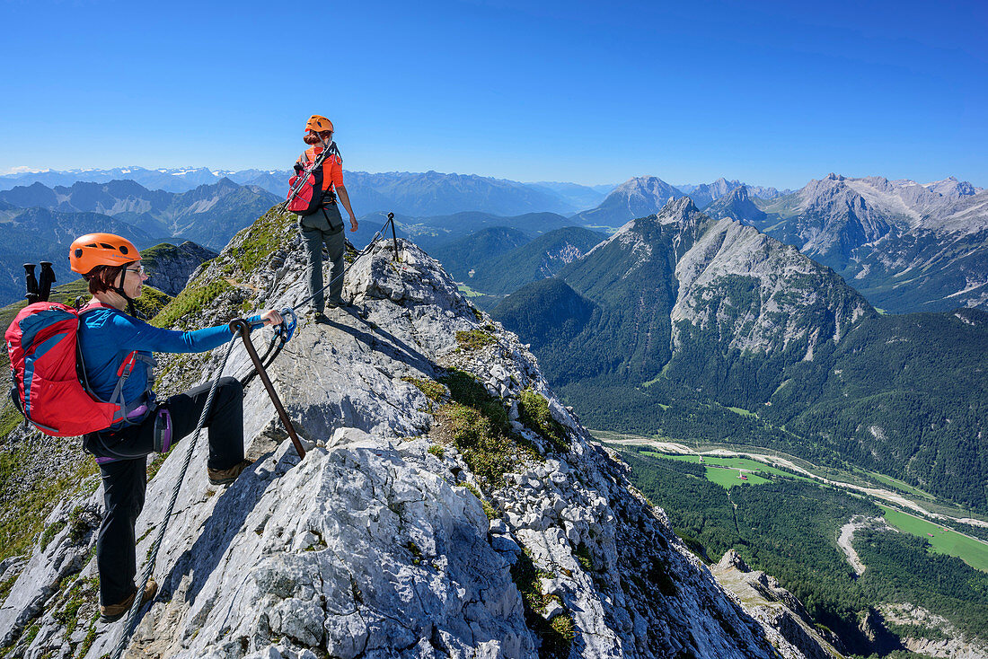 Two women climbing on fixed-rope route Mittenwalder Hoehenweg, Wetterstein range in background, fixed-rope route Mittenwalder Hoehenweg, Karwendel range, Upper Bavaria, Bavaria, Germany