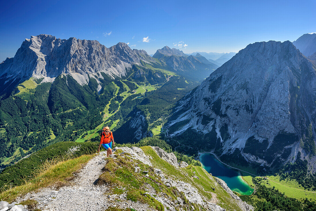 Frau beim Wandern steigt zur Ehrwalder Sonnenspitze auf, Wetterstein und Seebensee im Hintergrund, Ehrwalder Sonnenspitze, Mieminger Berge, Tirol, Österreich