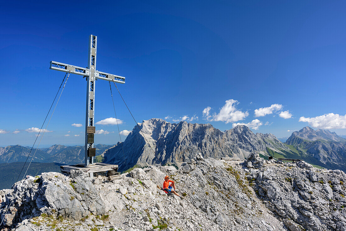 Woman sitting at summit of Ehrwalder Sonnenspitze, Wetterstein range with Zugspitze in background, Ehrwalder Sonnenspitze, Mieming range, Tyrol, Austria