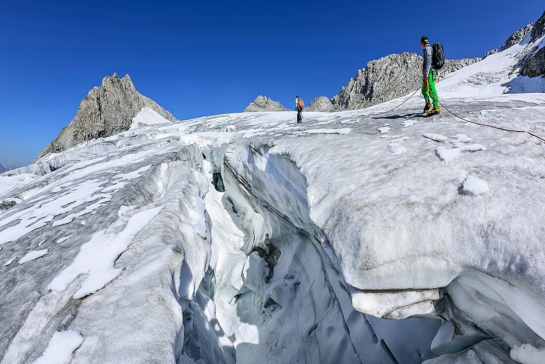 Mann und Frau steigen über spaltigen Gletscher auf, Kuchelmooskopf im Hintergrund, Kuchelmoosferner, Zillergrund, Reichenspitzgruppe, Zillertaler Alpen, Tirol, Österreich