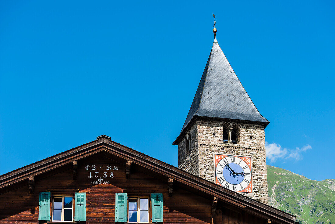 Ein altes Holzhaus und die Kirche im Dorfkern, Saas im Praettigau, Klosters, Kanton Graubünden, Schweiz