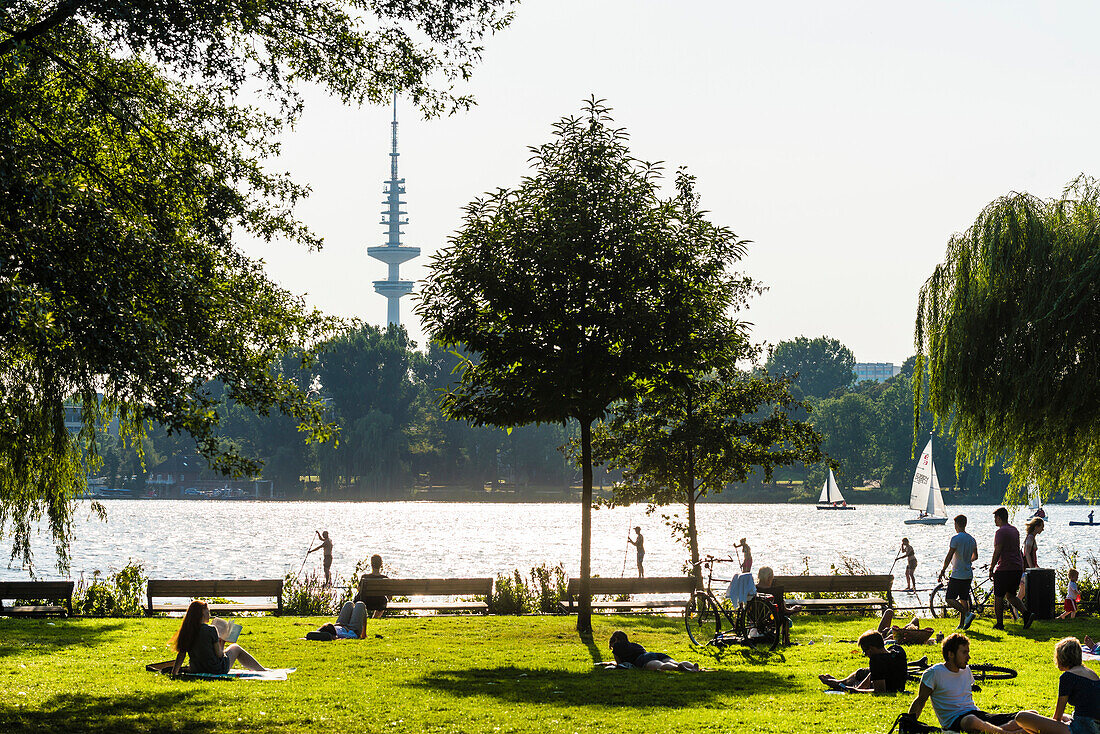 Locals and tourists taking a break at lake Aussenalster with a view to the television tower, Hamburg, Germany