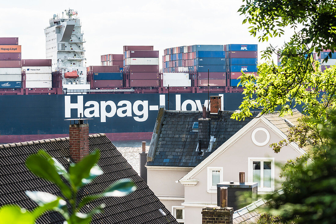 A container ship on the Elbe passes the staircase quarter in Blankenese, Hamburg, Germany
