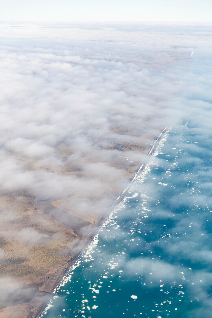 Aerial view of the North Slope coastline shrouded in a thin layer of clouds, icebergs floating in the Arctic Ocean, Deadhorse, Alaska, United States of America