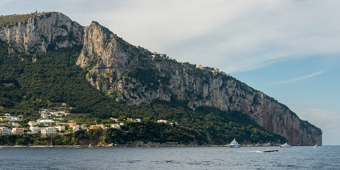 Tall, rugged cliffs along the island of Capri and the town of Capri, Capri, Campania, Italy