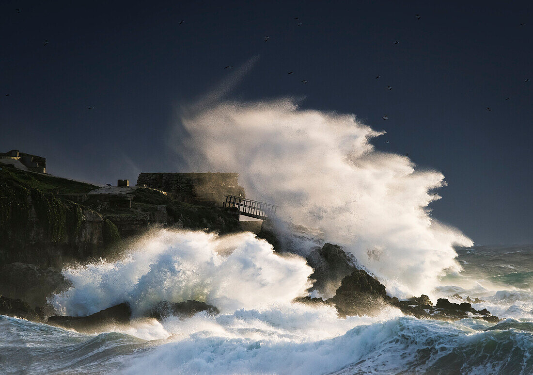 Wave crashing into shore and splashing onto the land above the cliffs, Isla de la Palomas, Tarifa, Cadiz, Andalusia, Spain