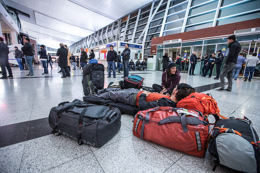 Zwei junge Sportler warten mit ihrem Gepäck auf dem Boden im Flughafen, Gudauri, Mzcheta-Mtianeti, Georgien