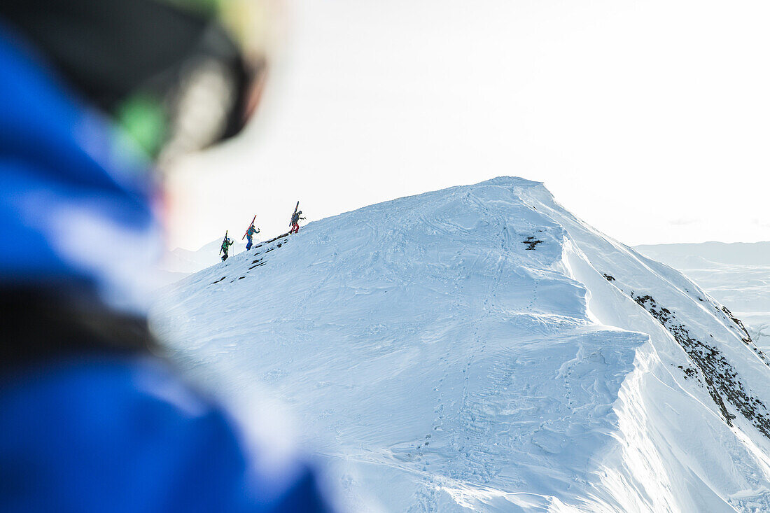 Drei junge Skifahrer laufen durch den Tiefschnee auf den Gipfel eines Berges, Gudauri, Mzcheta-Mtianeti, Georgien