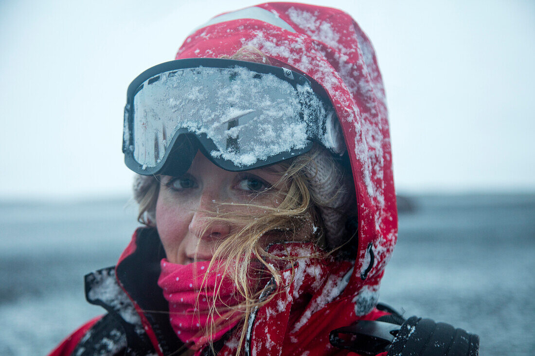Junge Frau blickt unter Skibrille hervor während Schneesturm, Whaler's Bay, Deception Island, Südshetland-Inseln, Antarktis