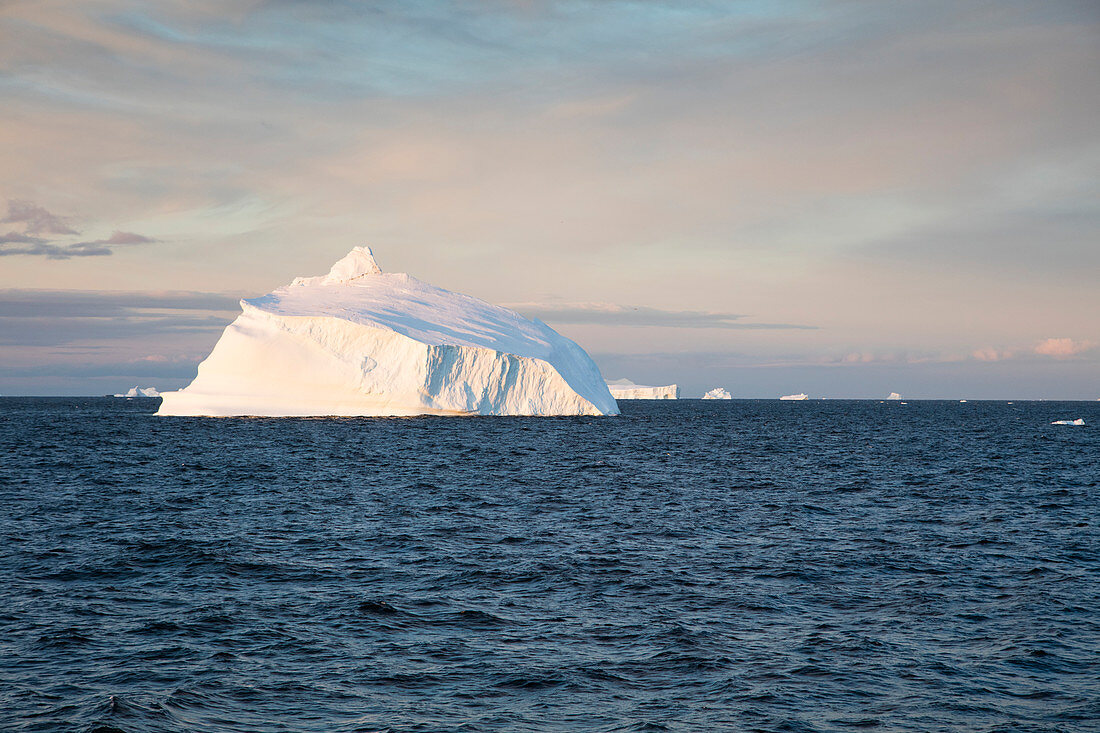 Eisberg und schneebedeckte Berge bei Sonnenuntergang, Gerlache Strait, Grahamland, Antarktische Halbinsel, Antarktis