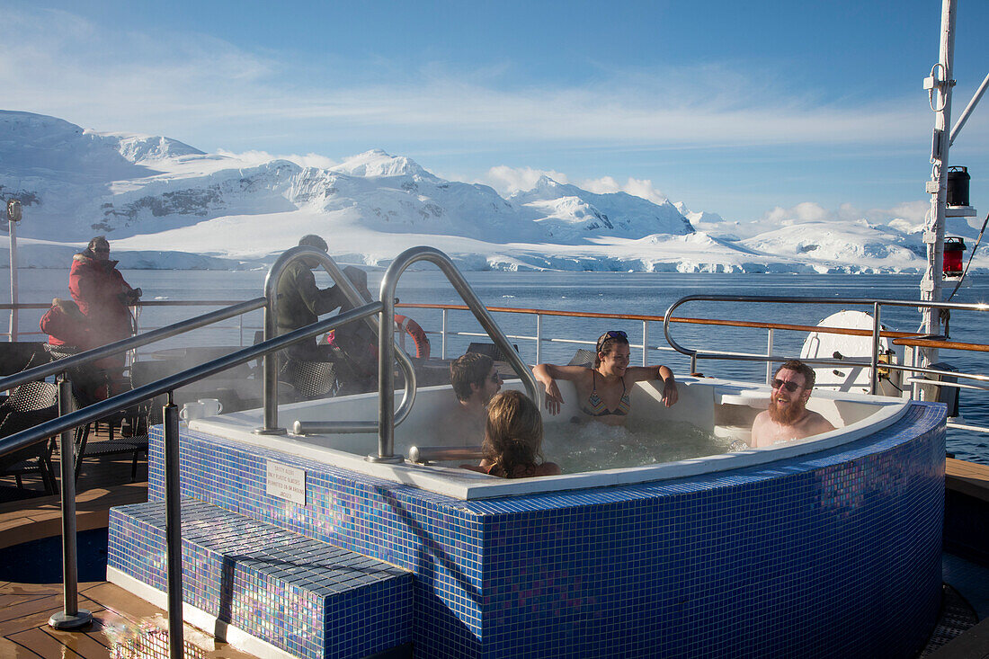 Passengers relax in a hot tub aboard expedition cruise ship MV Sea Spirit (Poseidon Expeditions) with view of snow-covered mountains Gerlache Strait, Graham Land, Antarctic Peninsula, Antarctica